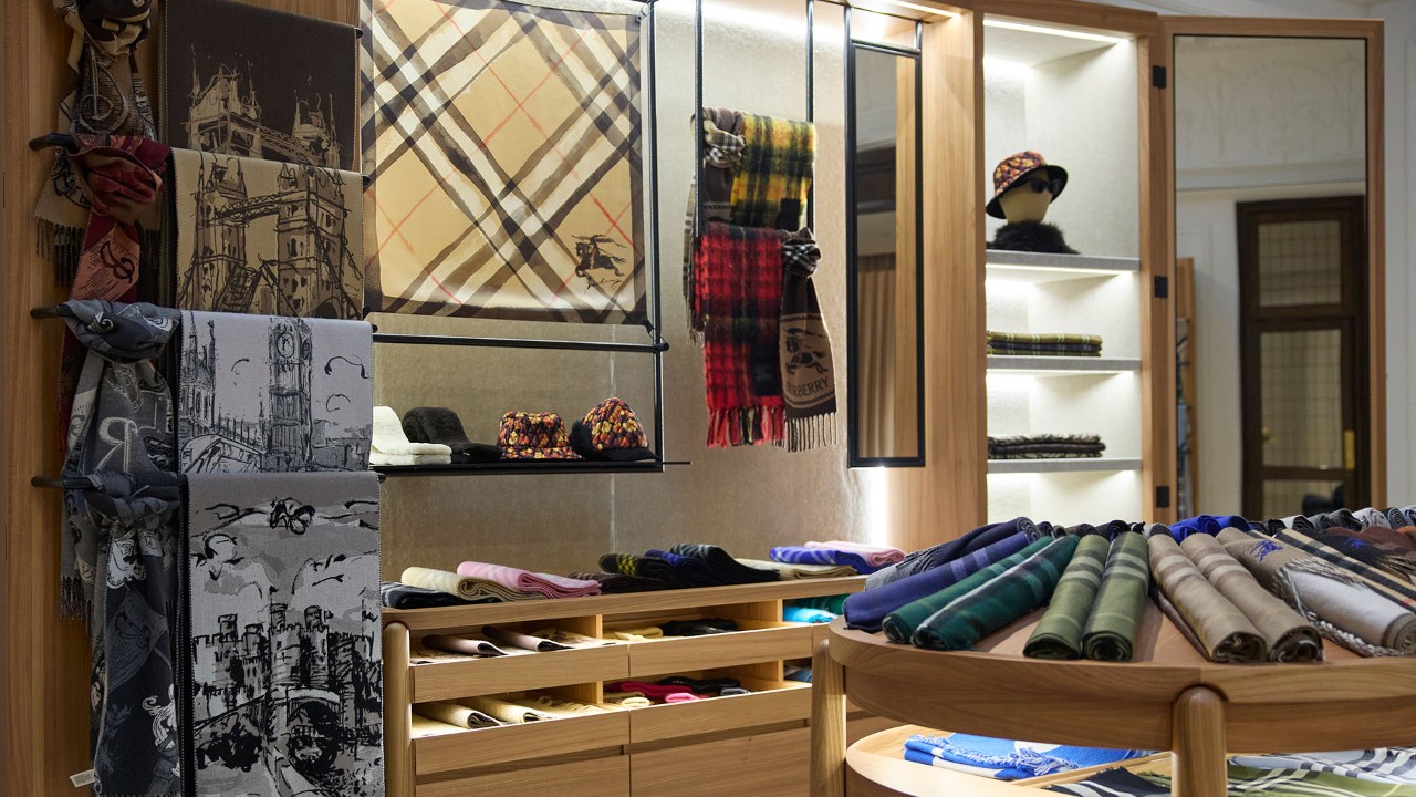 Interior of a Burberry store displaying signature check-pattern scarves, folded apparel, and fabric accessories.
