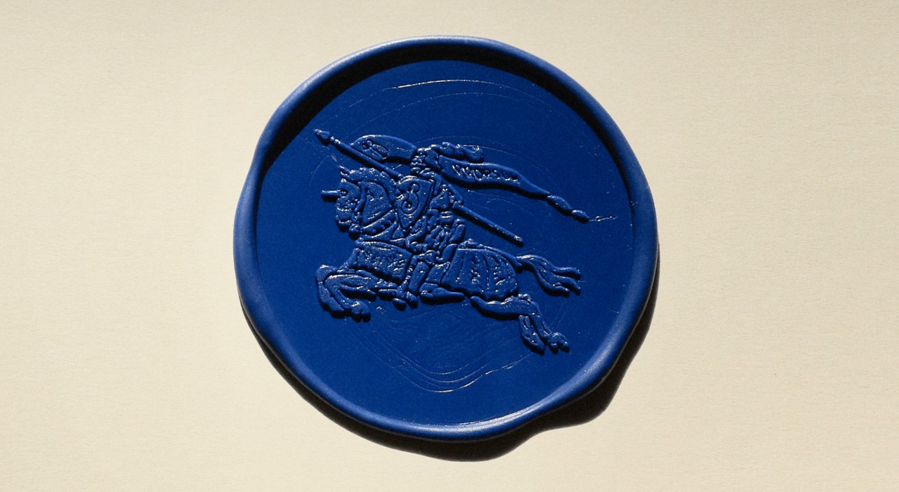 A close-up of Burberry’s equestrian knight emblem embossed on a royal blue wax seal, symbolising the brand’s heritage and spirit of progress.