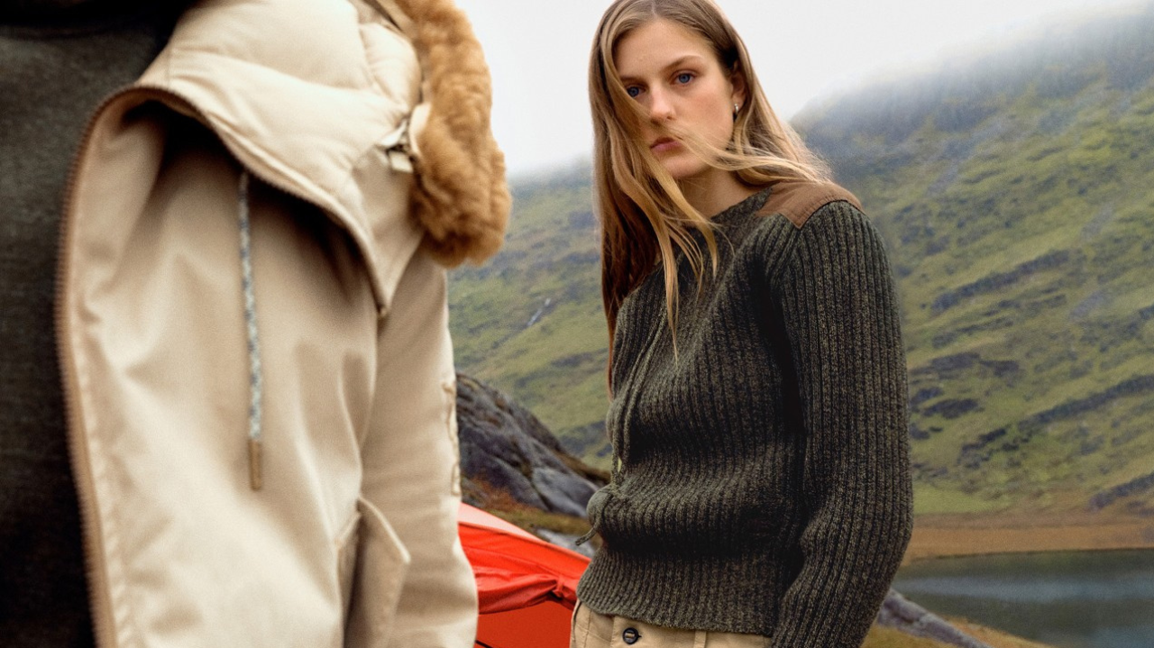 Editorial outdoor fashion campaign featuring textured knitwear, neutral layering, and rugged mountain scenery inspired by contemporary luxury adventure style.