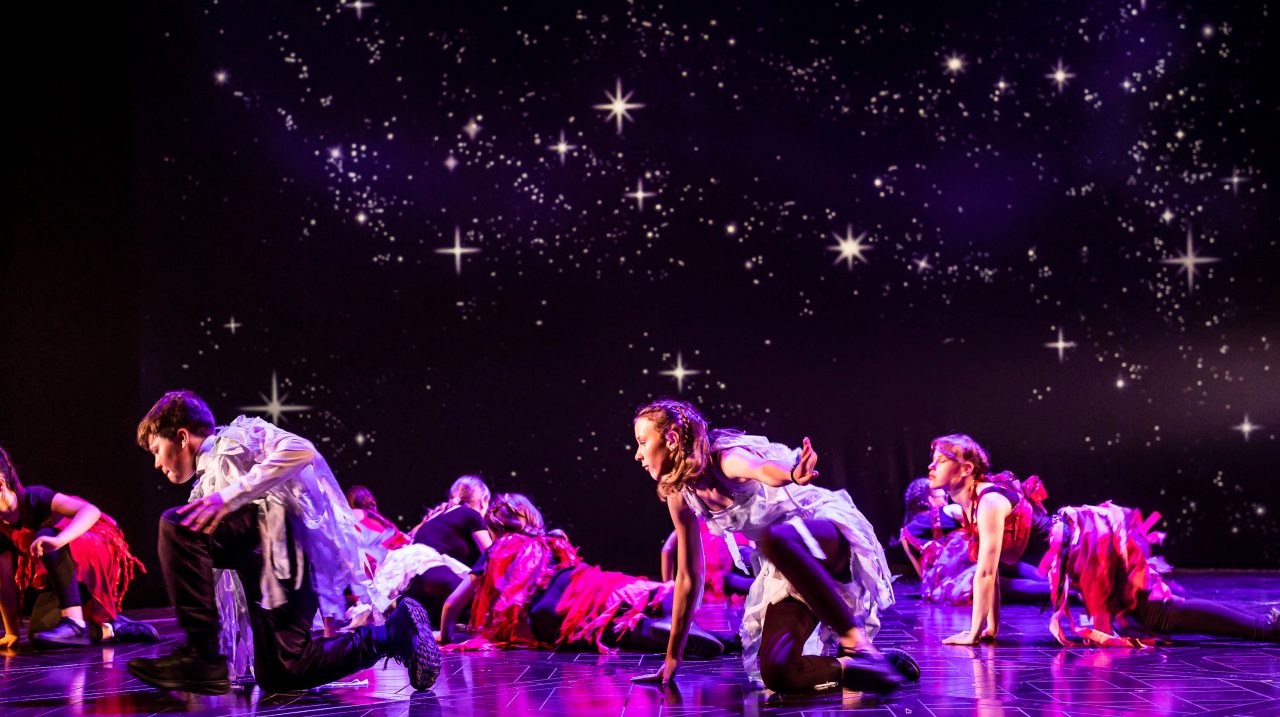 A group of young performers on stage under star-like lighting alongside an introduction to The Burberry Foundation, an independent charity focused on creativity, positive community impact, and building a sustainable future for young people.