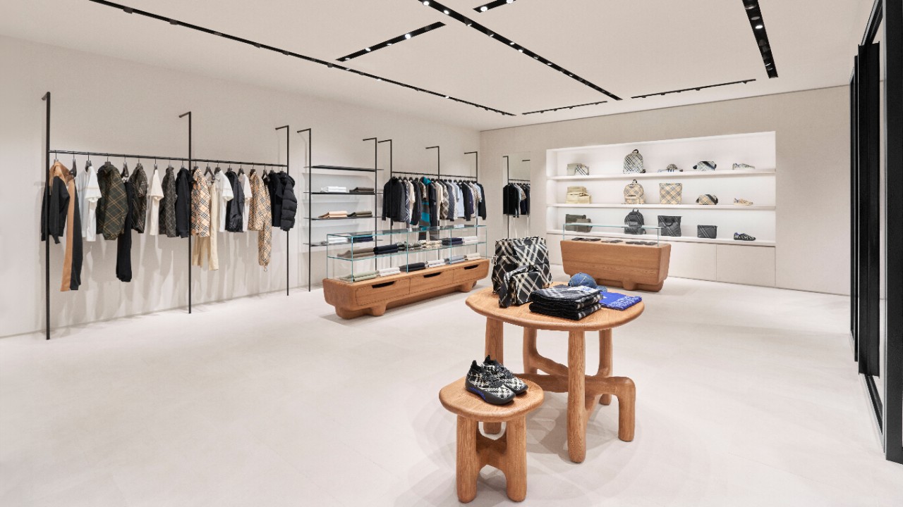Burberry retail store interior with clothing racks, shelves, and wooden display tables.