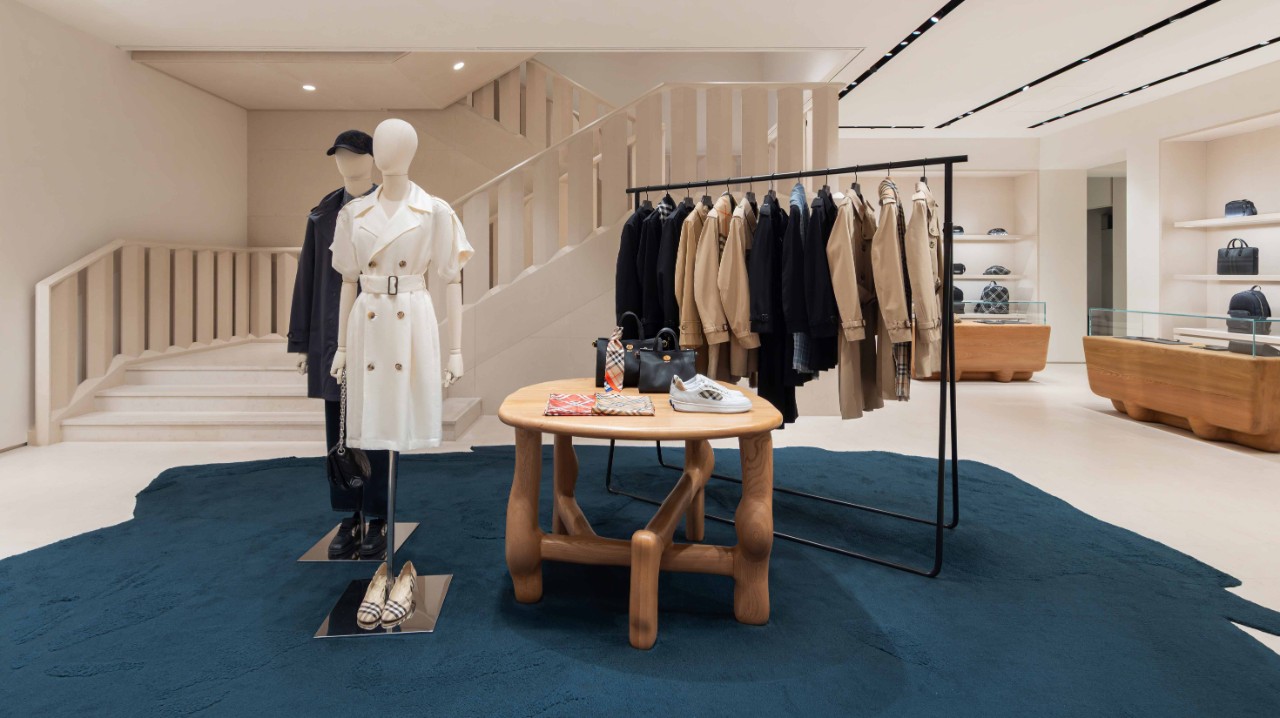 Image of a Burberry retail store interior featuring mannequins, a display table with accessories, and a clothing rail with trench coats and outerwear—supporting the Investment Case section.