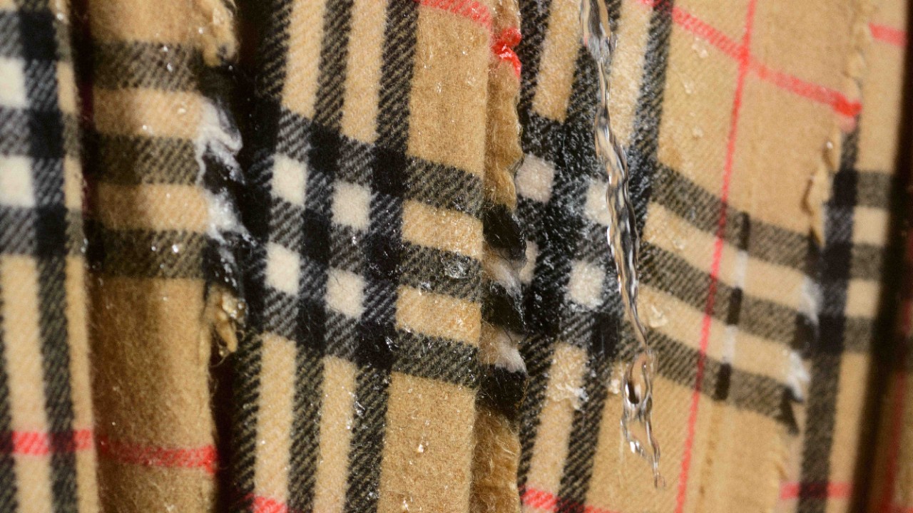 Close-up of Burberry’s iconic check cashmere fabric during water resistance testing, highlighting craftsmanship and material excellence.