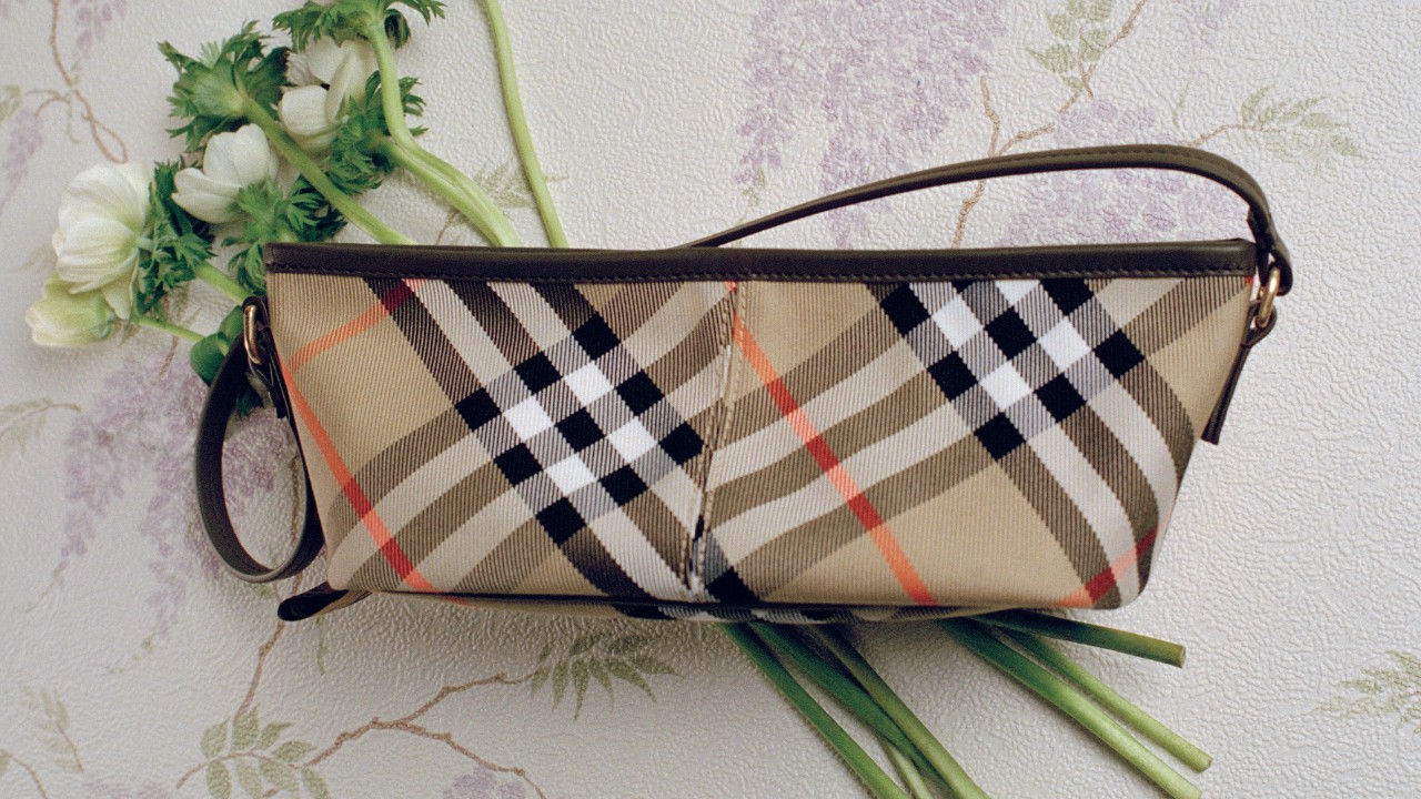 Image of a Burberry handbag with the signature check pattern placed on a floral surface with white flowers. Access information on registering for electronic shareholder communications.